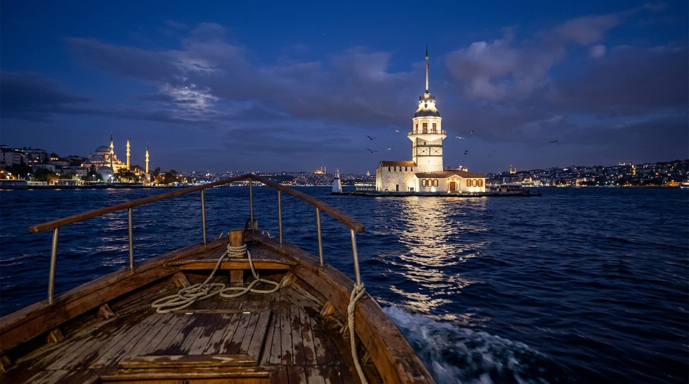 View from the bow of a small passenger boat on dark blue water approaching the Maiden's Tower at dusk
