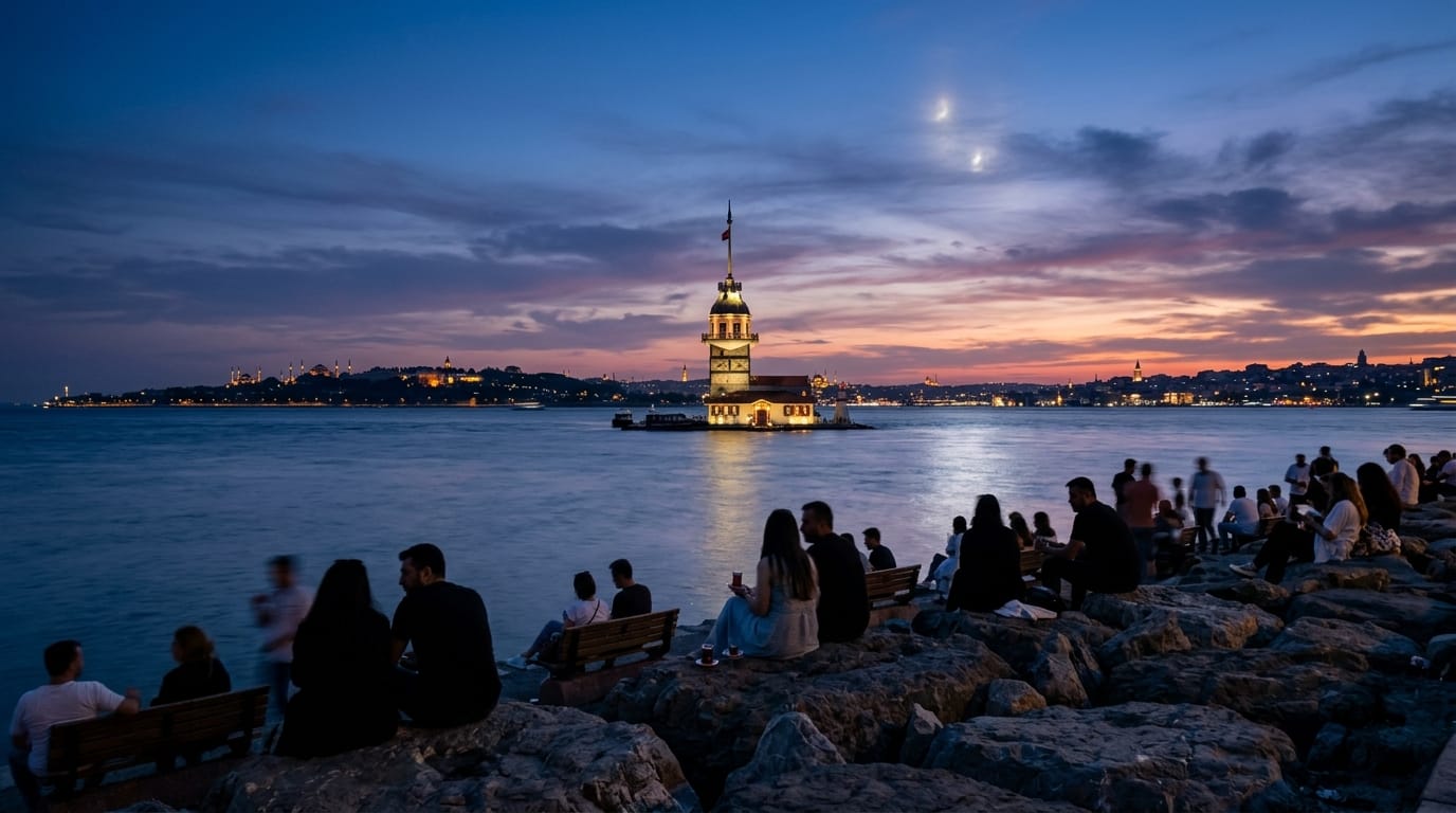 People silhouetted on the Salacak shoreline at sunset, looking toward the Maiden's Tower with the old-city skyline across the water